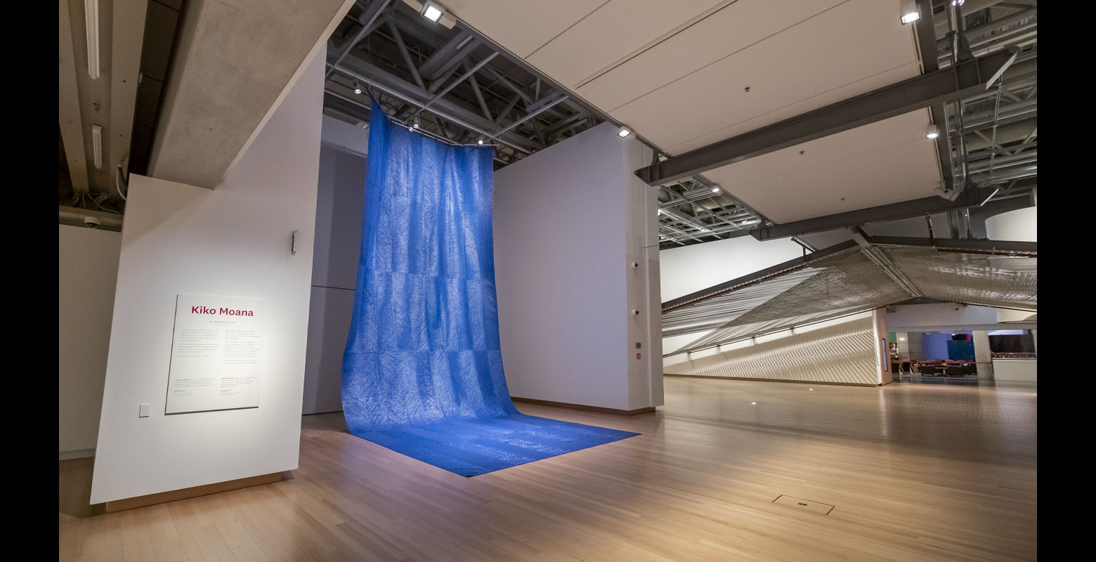 Large sheets of blue tarpaulin stitched together as one hang from the ceiling of the gallery and drape across the floor, resembling a waterfall.