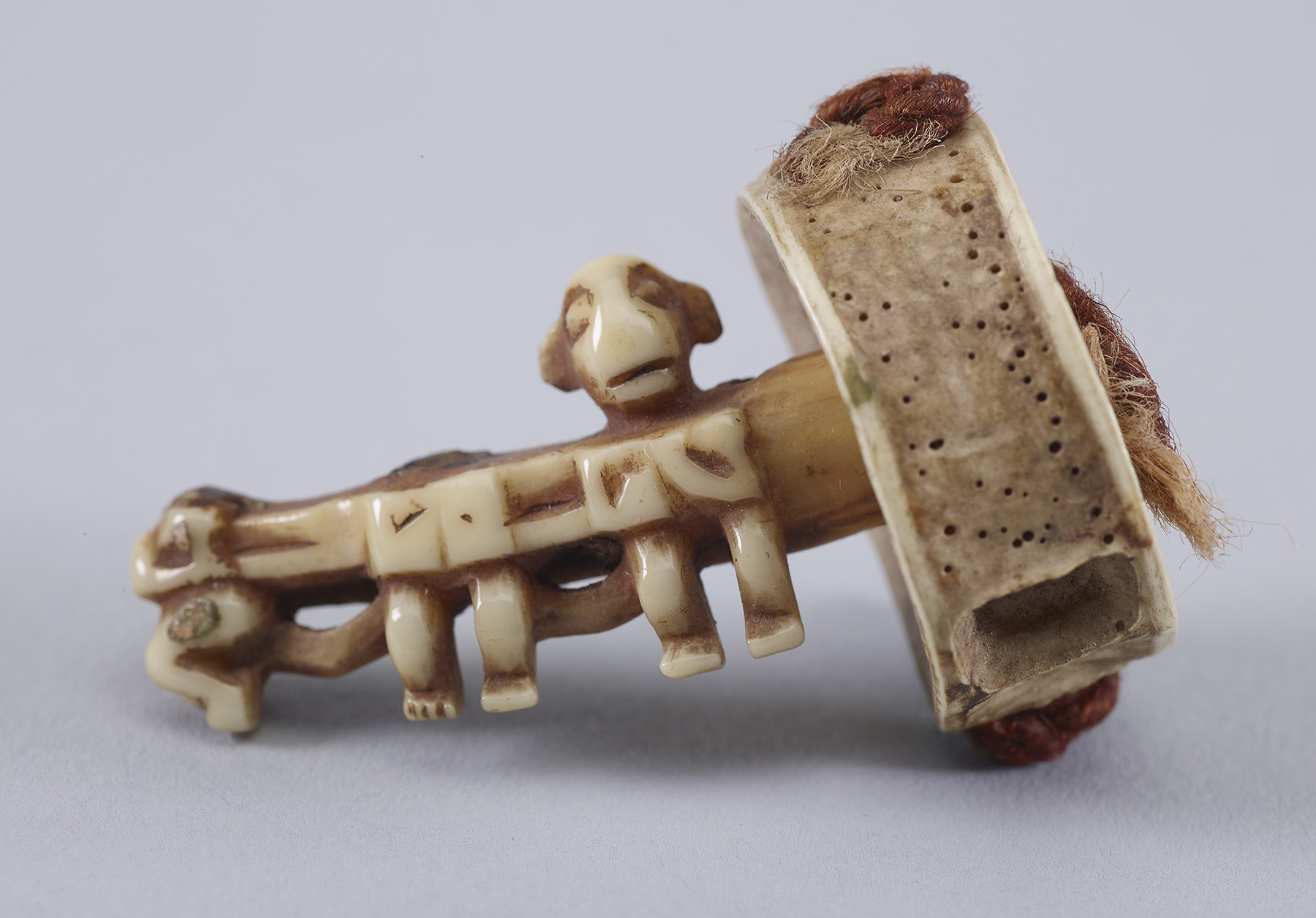 Ear ornament carved from whale teeth with human figures