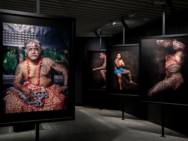 Inside an exhibition, large photographs of tattooed men hang on the walls