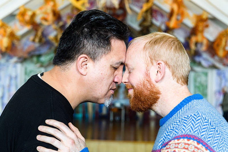 Two men press their noses together for hongi