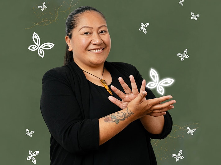 NZSL Awards night. Photo  courtesy of NZSL Board A woman is using her hands to say sign language and smiling at the camera.