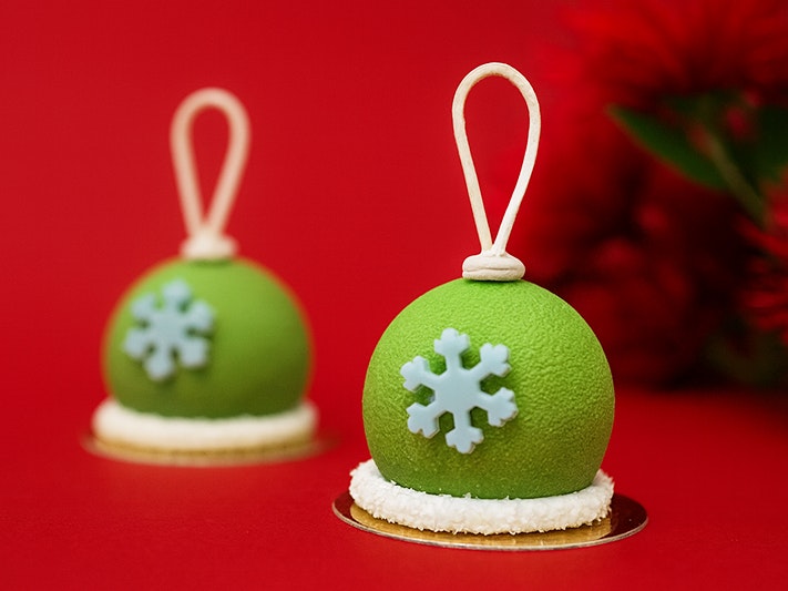 Te Papa Cafe Kirihimete ki Te Papa Specials, 2025. Photo by Caitlin Dorrington Two green desserts, shaped like bells with a blue snowflake on the front.