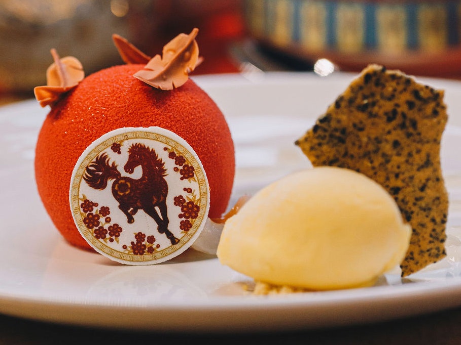 Photo by Larissa Warren 2026 A plate of dessert with some ice cream, cake and a themed orange ball with a horse on it.