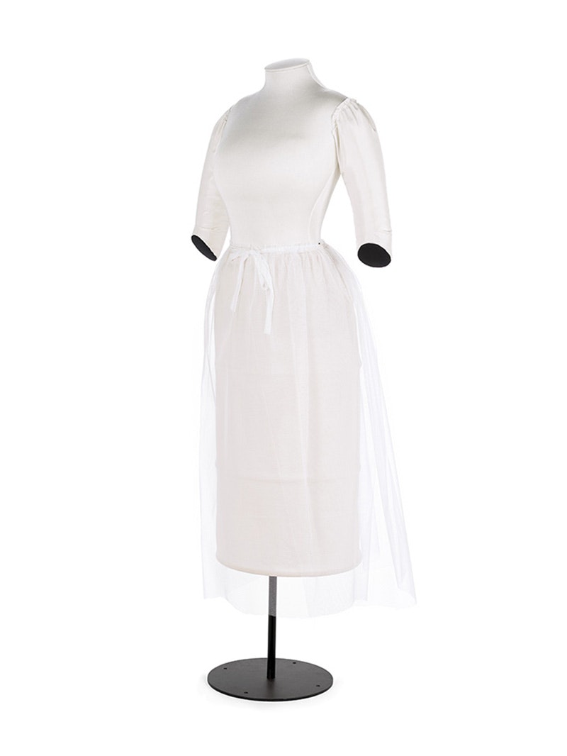 A white dressmakers mount with white padding for arms and a see-through gauze skirt