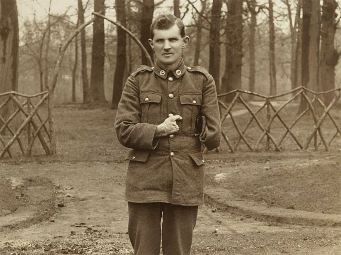 A soldier with one arm poses for a picture in a park