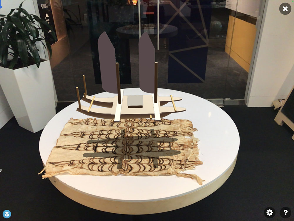 A digital vaka (canoe) is superimposed onto a table