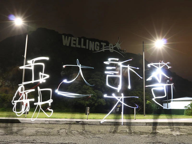 A photo of someone writing Chinese using light outside in the dark
