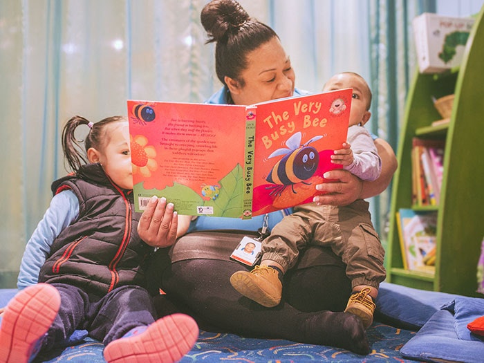 A woman reads a book to two children