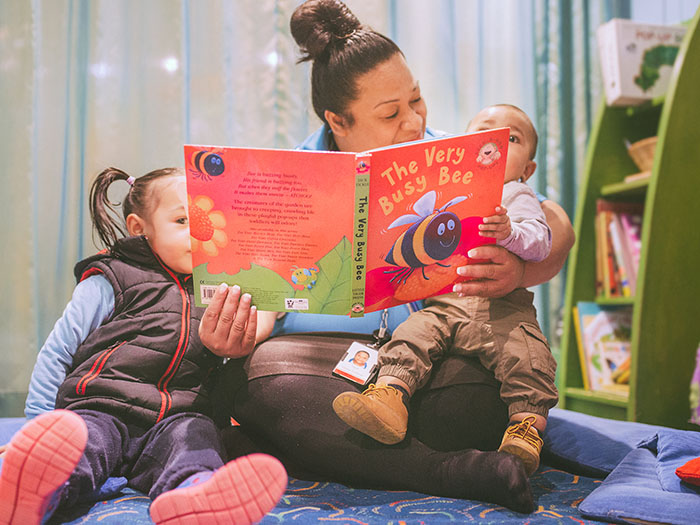 A woman reads a book to two children