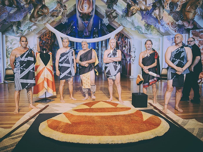 Powhiri for the return of the feather cloak ('ahu 'ula), 2016. Te Papa Hawaiian delegates in ceremonial garments standing over the feathered cloak at the powhiri at Te Papa's marae