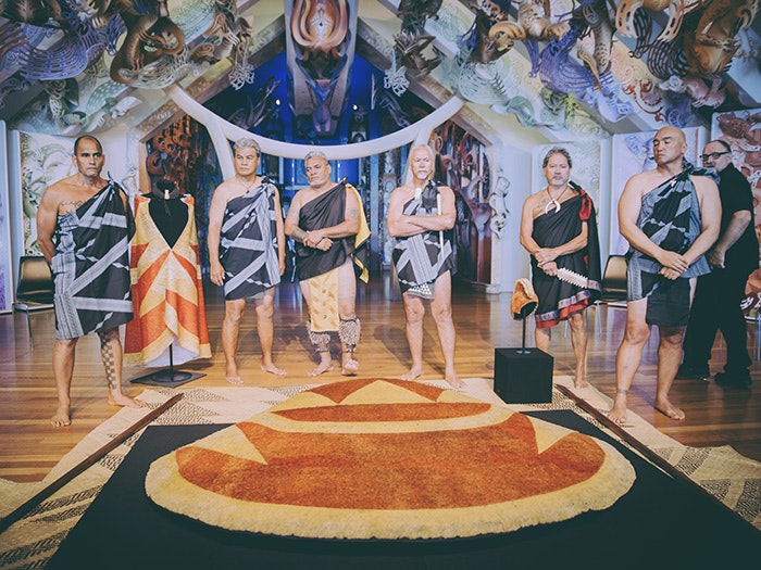 Hawaiian delegates in ceremonial garments standing over the feathered cloak at the powhiri at Te Papa's marae