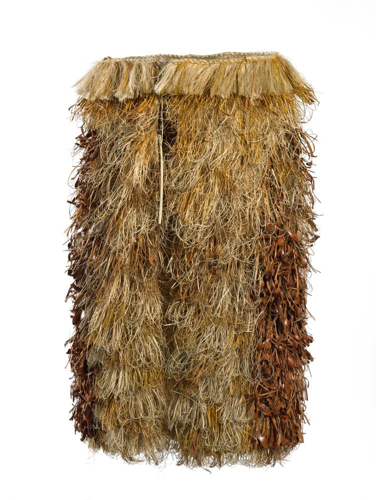 A round cloak on a frame tied at the top. It is made of flax, bird bone and glossy brown leaves.