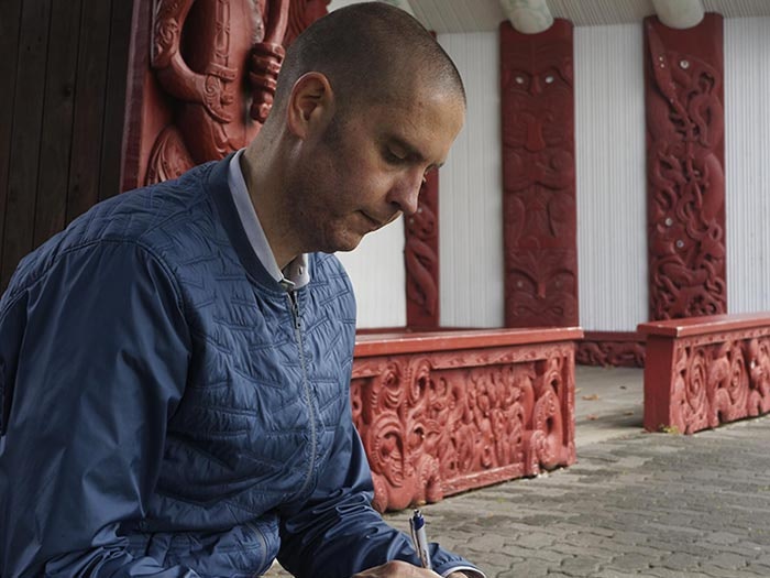 Photograph by Haru Sameshima of Studio La Gonda Author writing in front of meeting house
