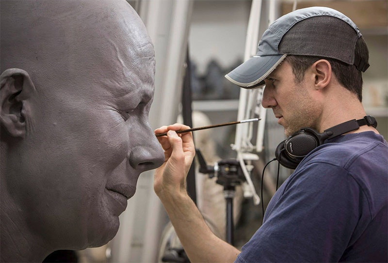 Painting one of the giant model's faces.