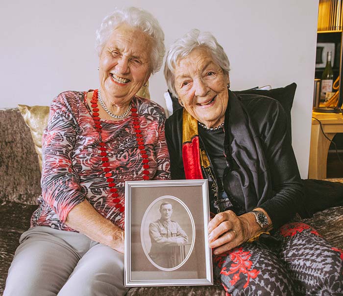 Billie and Peggy sit holding a photograph of their father who fought at Gallipoli