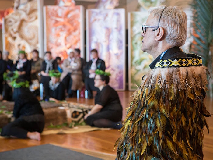 A man in a feathered cloak at a repatriation ceremony at Te Papa's marae
