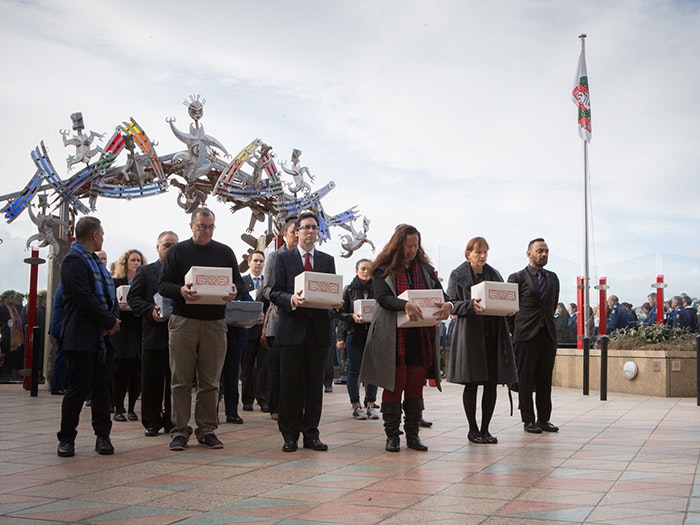 A group of people hold boxes containing Māori and Moriori skeletal remains