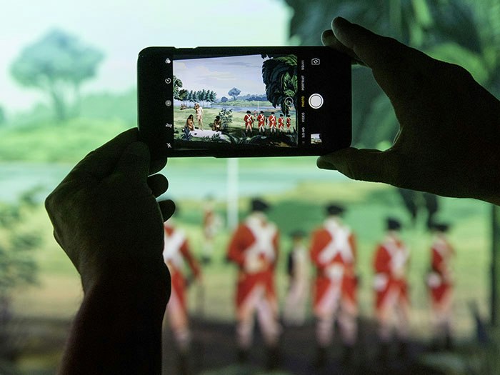 Close up of a person taking a photograph of Lisa Reihana's Emissaries, focusing on the screen of the camera