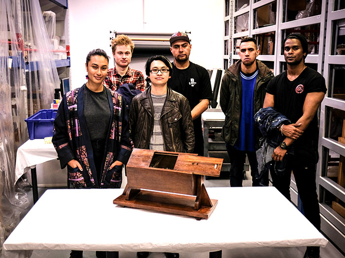 People pose for a photo behind a table on which sits a wooden ballot box