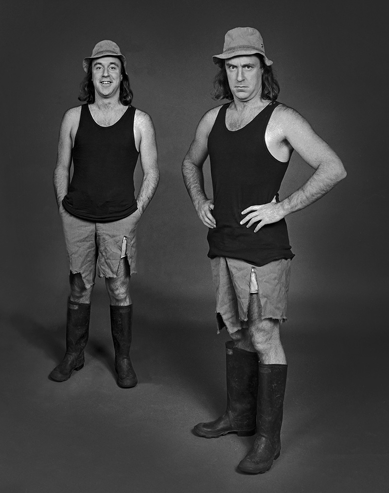 Comedian John Clarke in character as Fred Dagg wearing gumboots, tight shorts, and a floppy hat