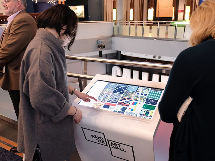 A woman uses the kiosk to browse art works to send to the wall