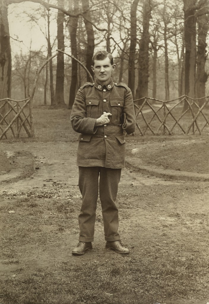 A one-armed soldier has his portrait taken in a field