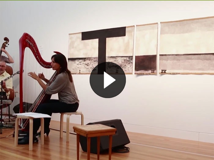 A lady plays the heart in front of Colin McCahon's work