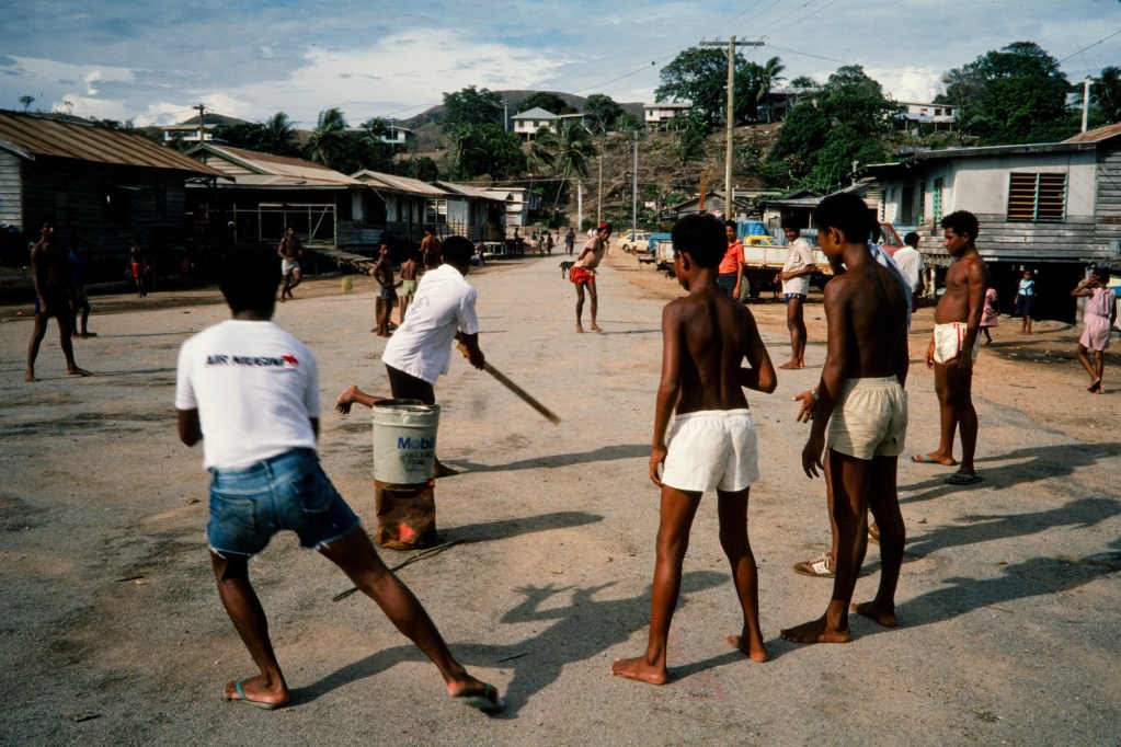 Young Papua New Guinean boys play cricket in the street