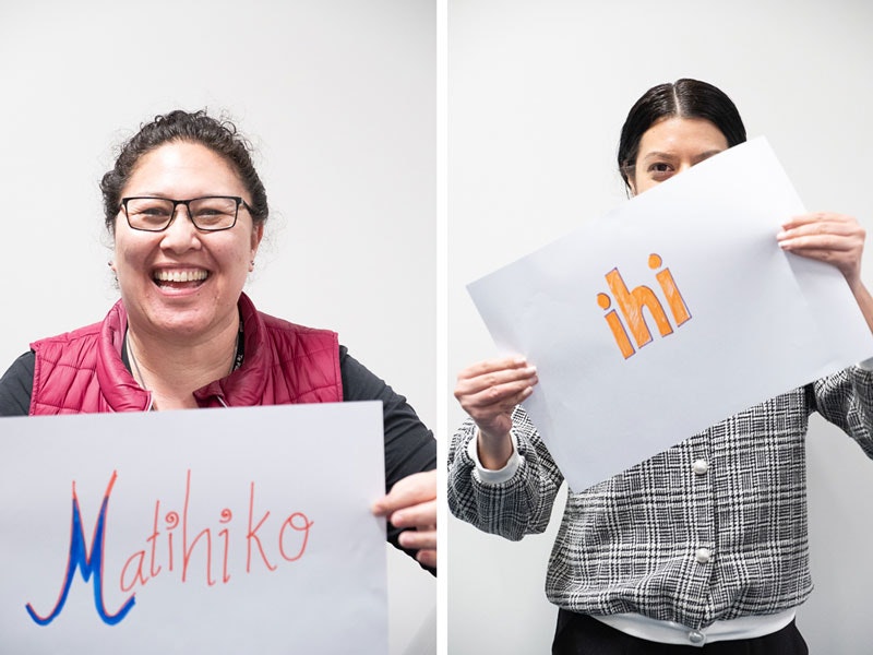 Two ladies holding up signs with Māori words 'ihi' and 'Matihiko' on them