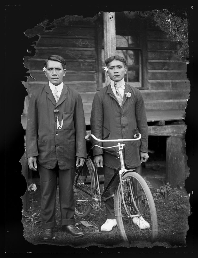 Two man dress in their best stand by a bicycle