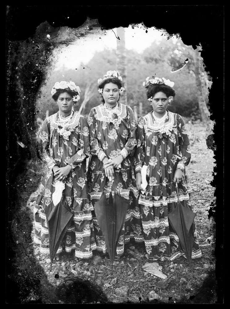 Three ladies in matching outfits holding umbrellas