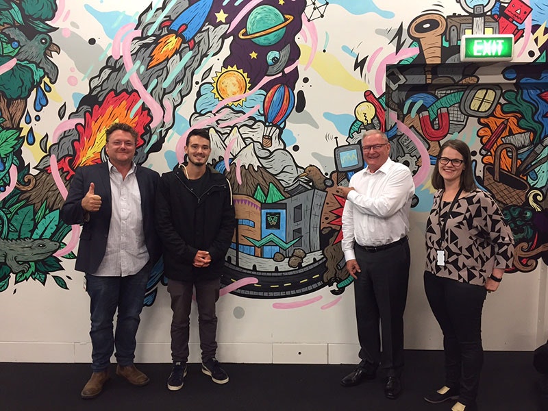 Hīnātore's Matt Richards, Gwil, Te Papa Chief Executive Rick Ellis, and Hīnātore's Miri Young in front of the wall illustration
