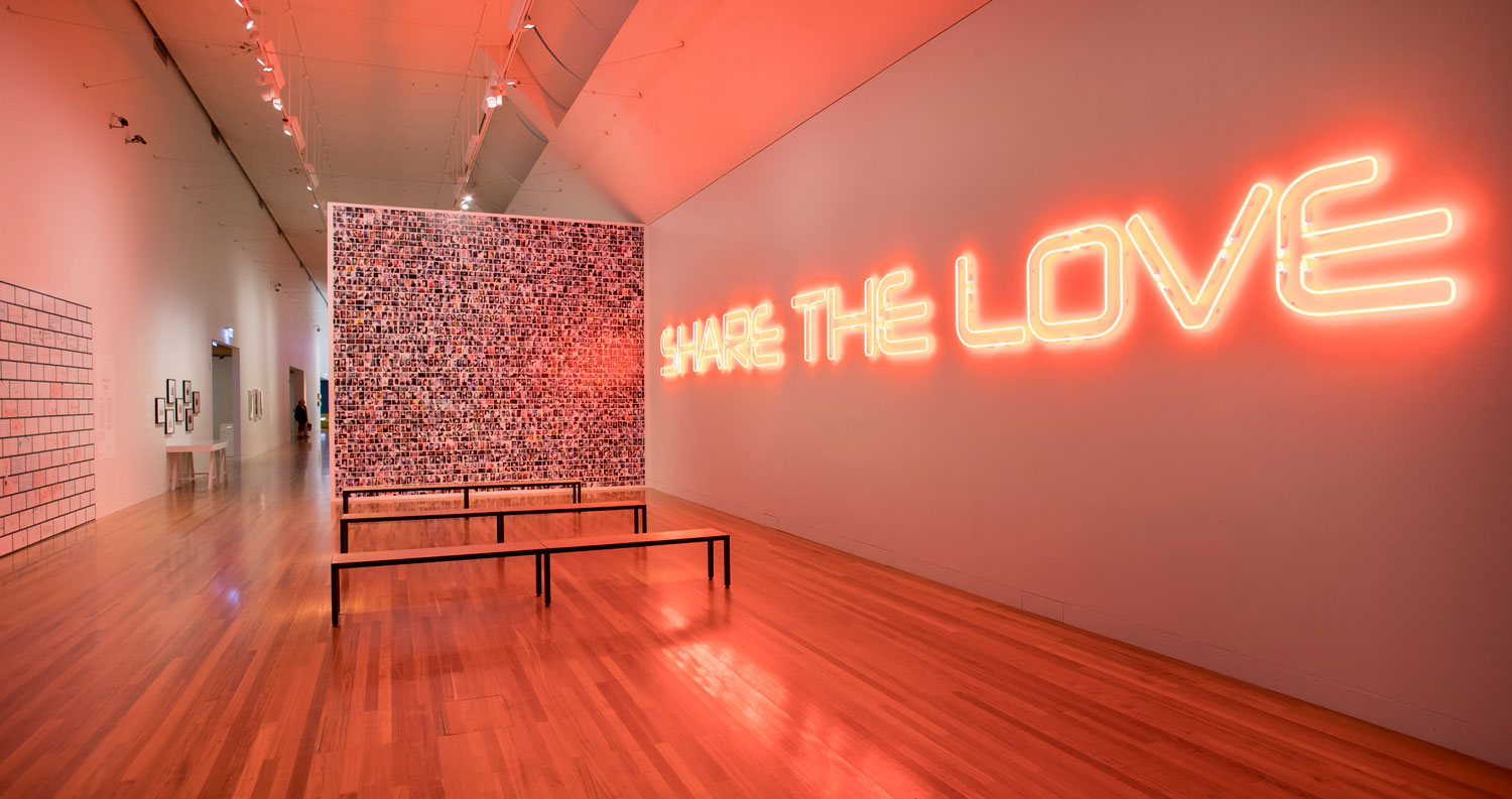 A gallery wall with an neon sign spelling the words 'Share the Love'