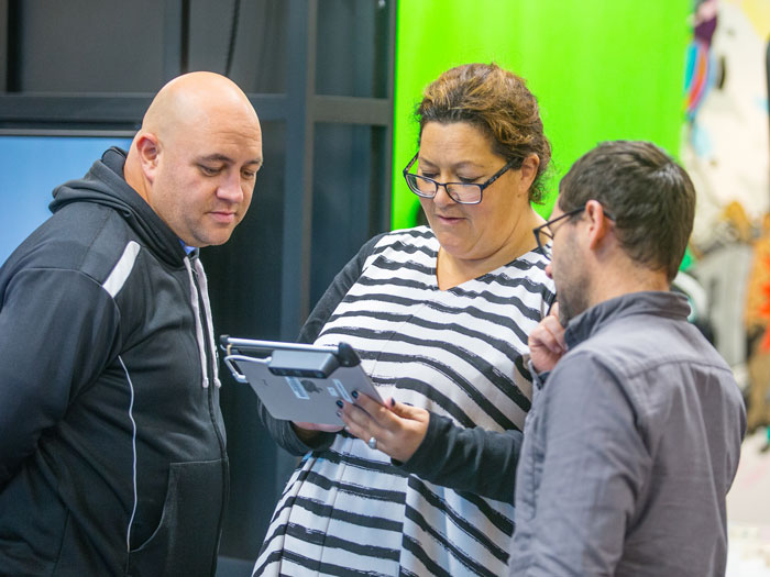 Teachers crowd look at a tablet with a Te Papa educator