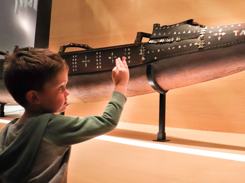 Small child looks at a Pacific vaka