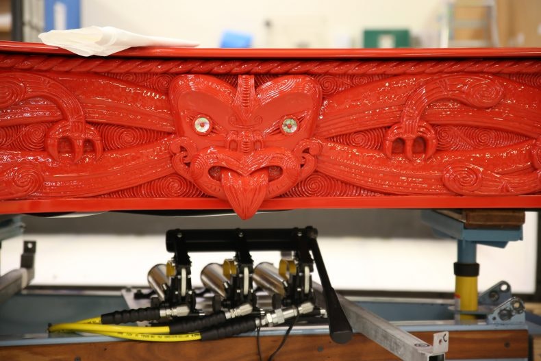 Close-up of carving on a red piano with Māori design