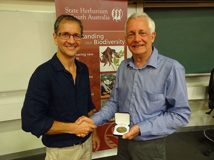 Two men, one holding a medal, shake hands