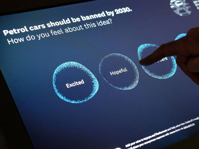 Visitor plays with a digital screen on it the words says 'Petrol cars should be banned by 2030. How do you feel about this idea?'