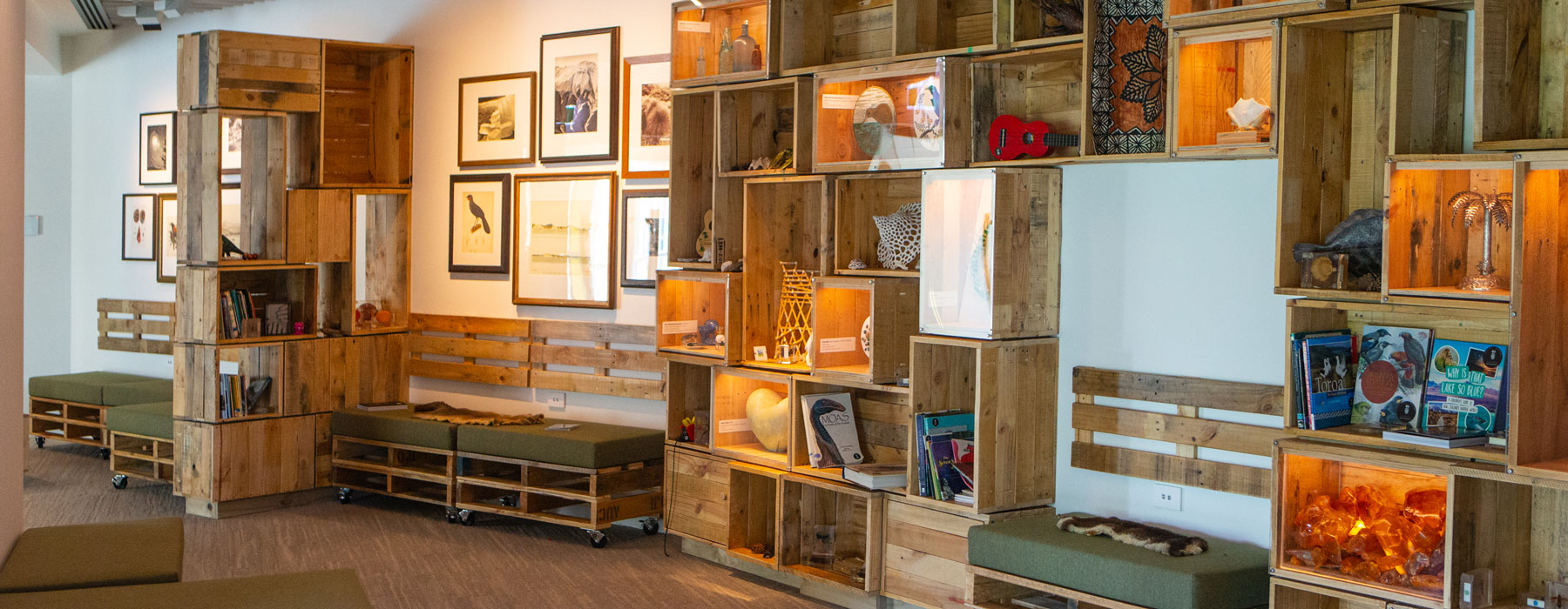 Walls covered in wooden boxes with objects inside, and lots of sofas