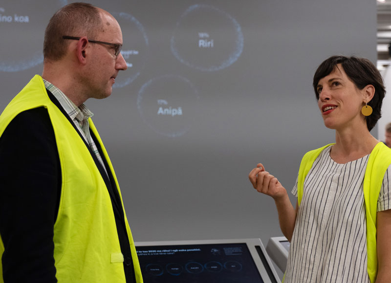 Two people talk in front of an interactive
