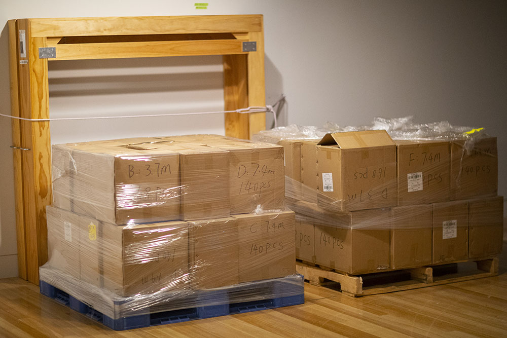 Two large crates of boxes sit on the floor in the gallery