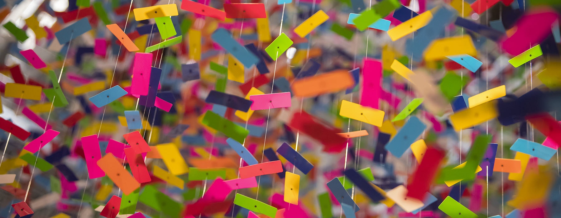 An extreme close-up of brightly-coloured pieces of plastic suspended from the ceiling