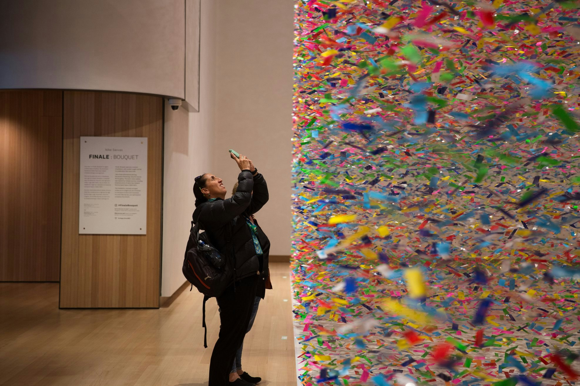 A visitor trying to capture the scale of a colourful artwork