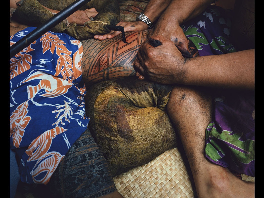 Mark Adams, Farwood Drive, Henderson, west Auckland Tattooing Uli Tufuga tatatau: Su‘a Tavui Pasina Iosefo Ah Ken, 1982, print. Courtesy of the artist. Te Papa (TMP036153) Close-up of a person getting a Samoan tattoo