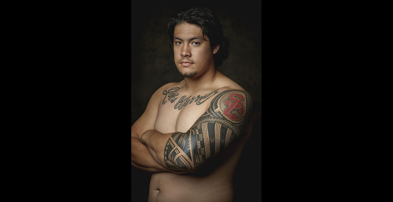 A man poses to show off his arm and chest tattoos