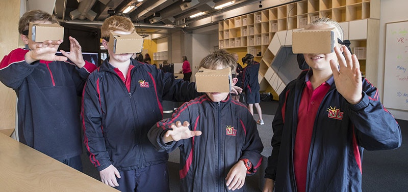 Four children wear cardboard virtual reality viewers on their faces