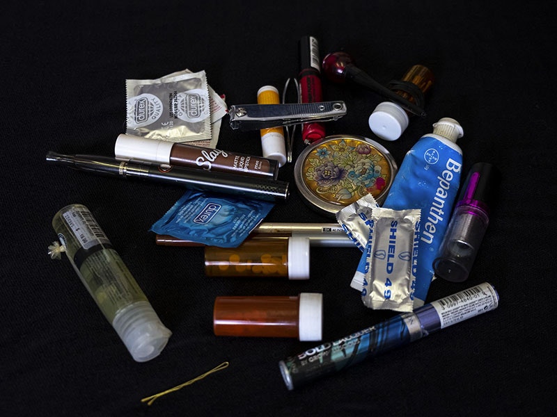 An array of items, including lubricant, condoms, lipstick nail clippers, pills, a hairclip, an other  things