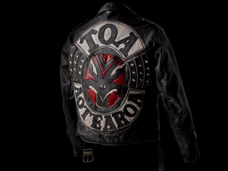 Jacket, Once Were Warriors, 1994. Design by Michael Kane and Pauline Pohatu. Leather, paint, metal. Purchased 2017. Te Papa (ME024268) A black leather gang jacket with the word 'Toa Aotearoa' on it