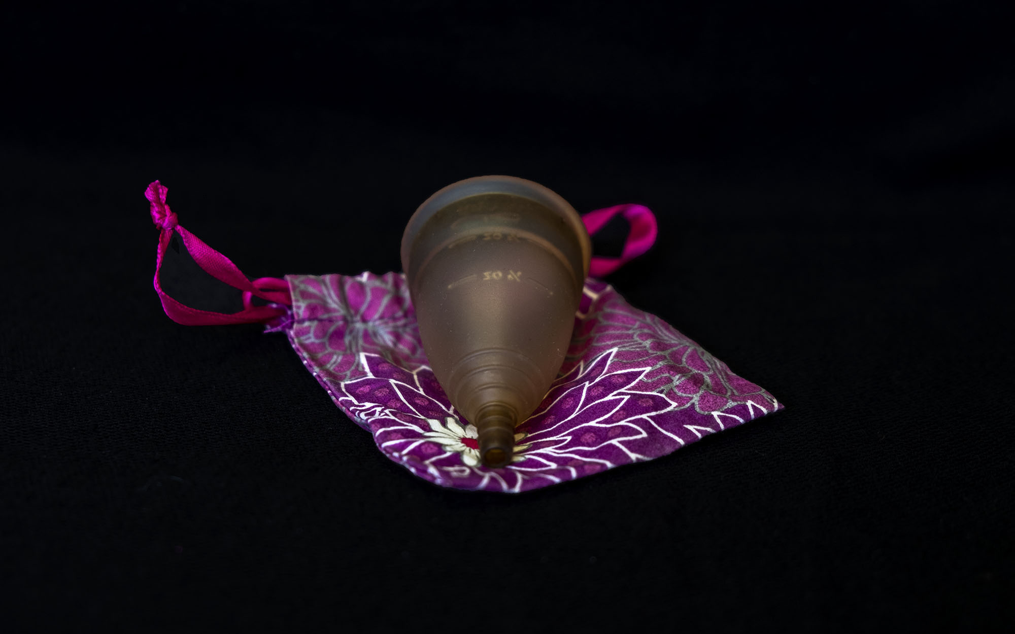 A menstrual cup sits on a purple bag