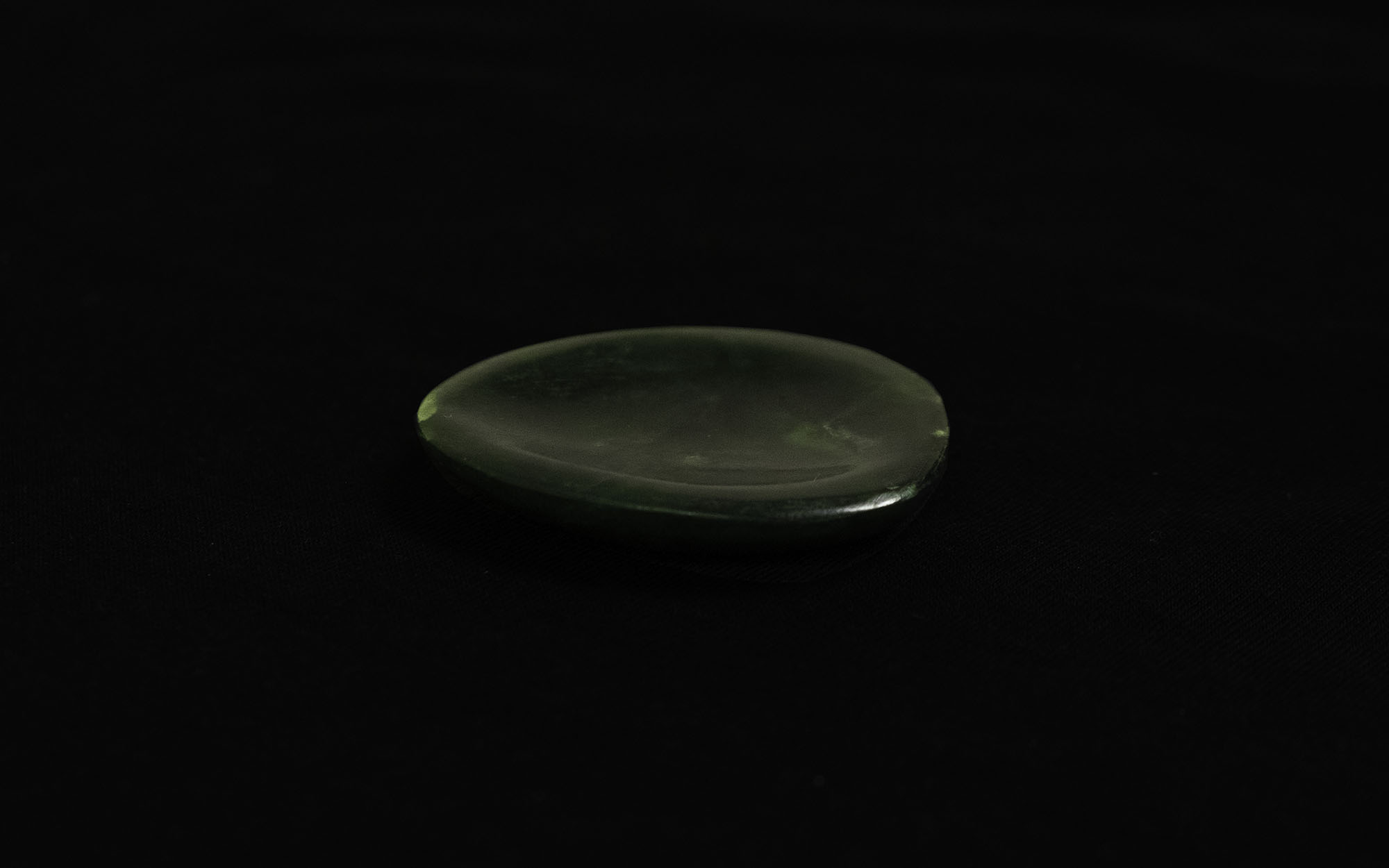 A small carved piece of pounamu, hollowed as if it is a small bowl